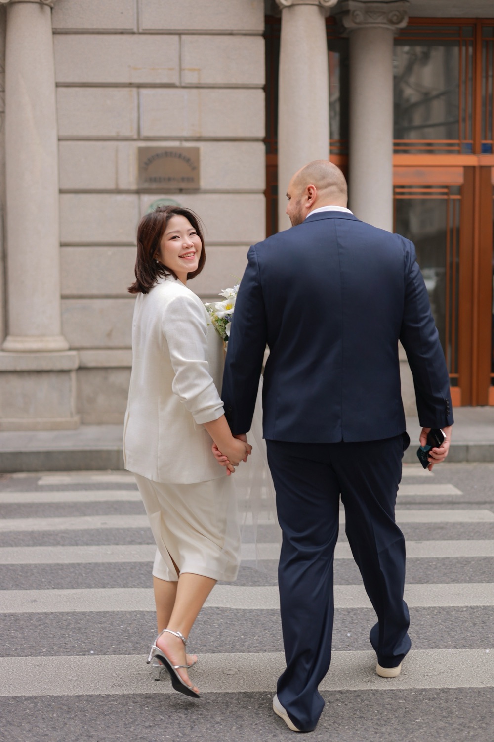 Walking hand in hand, glancing back with a smile